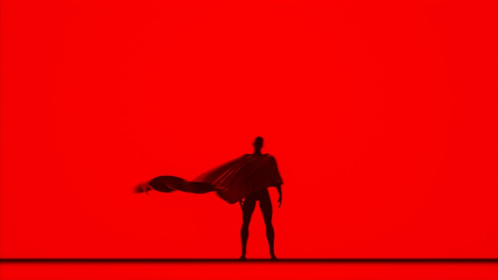 Caped person stands in silhouette.