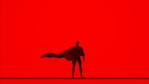 Caped person stands in silhouette.